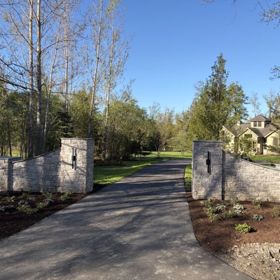Austin Rustic Ashlar Residential Driveway Entrance Matched stone pillars and curved wing walls clad in Austin Rustic Ashlar at a residential driveway entrance.