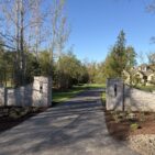 Matched stone pillars and curved wing walls clad in Austin Rustic Ashlar at a residential driveway entrance.