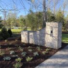 Side view of Austin Rustic Ashlar wing wall and pillar at a residential property, with new landscape plantings.
