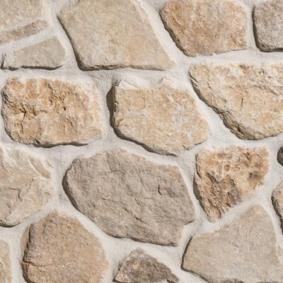 Heritage Buff Mosaic thin veneer close-up showing rounded, irregular light tan and golden sandstone stones set in wide mortar joints