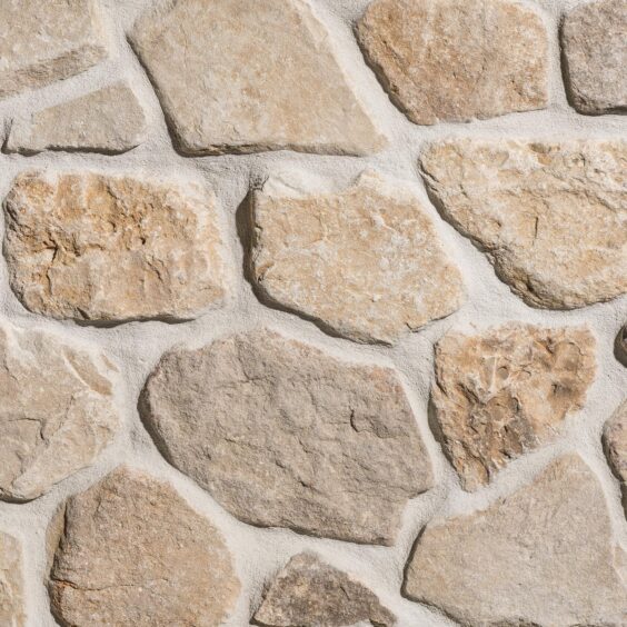 VTWMHB Heritage Buff Mosaic Thin Veneer Sandstone Close Up Heritage Buff Mosaic thin veneer close-up showing rounded, irregular light tan and golden sandstone stones set in wide mortar joints